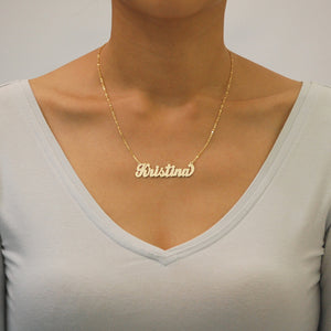 Woman wearing oversized handcrafted solid gold cursive script nameplate necklace