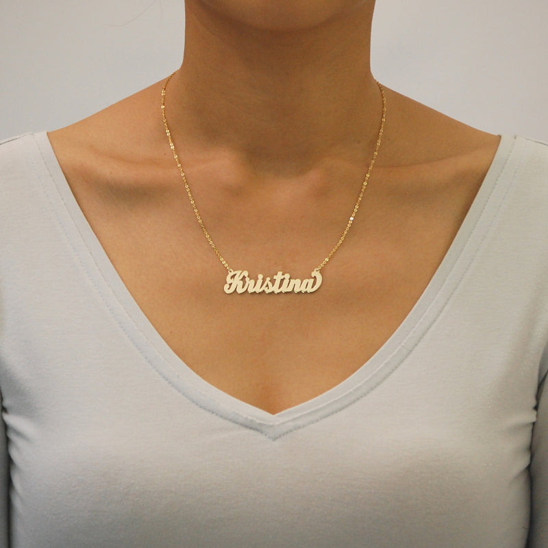 Woman wearing oversized handcrafted solid gold cursive script nameplate necklace