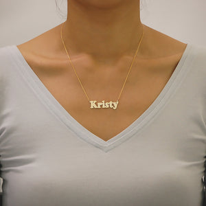 Model wearing a personalized solid gold bold block letter nameplate necklace.