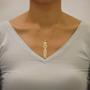 Woman wearing personalized solid gold vertical name pendant attached to a fine gold chain around the neck