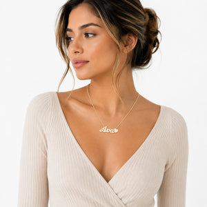 Close-up of a model wearing a personalized script name pendant layered with fine gold jewelry.