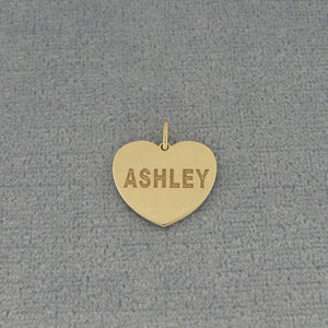 Personalized yellow gold heart charm pendant engraved ASHLEY on textured gray fabric