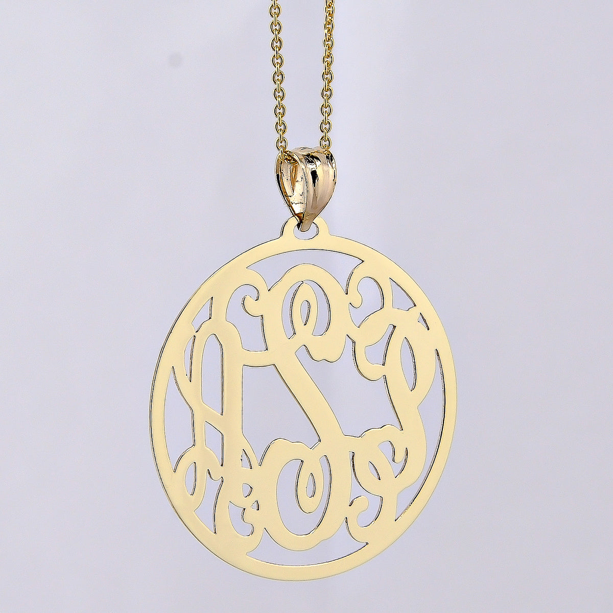 10k or 14k solid gold three-initial circle monogram pendant on a gold chain against a lavender background