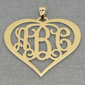 Close-up of a solid gold 3-initial heart monogram pendant on a gray background.