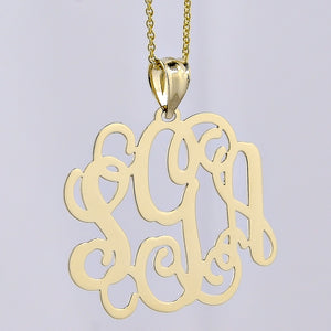 Close-up front view of a solid yellow gold three-initial custom monogram pendant on a fine chain.