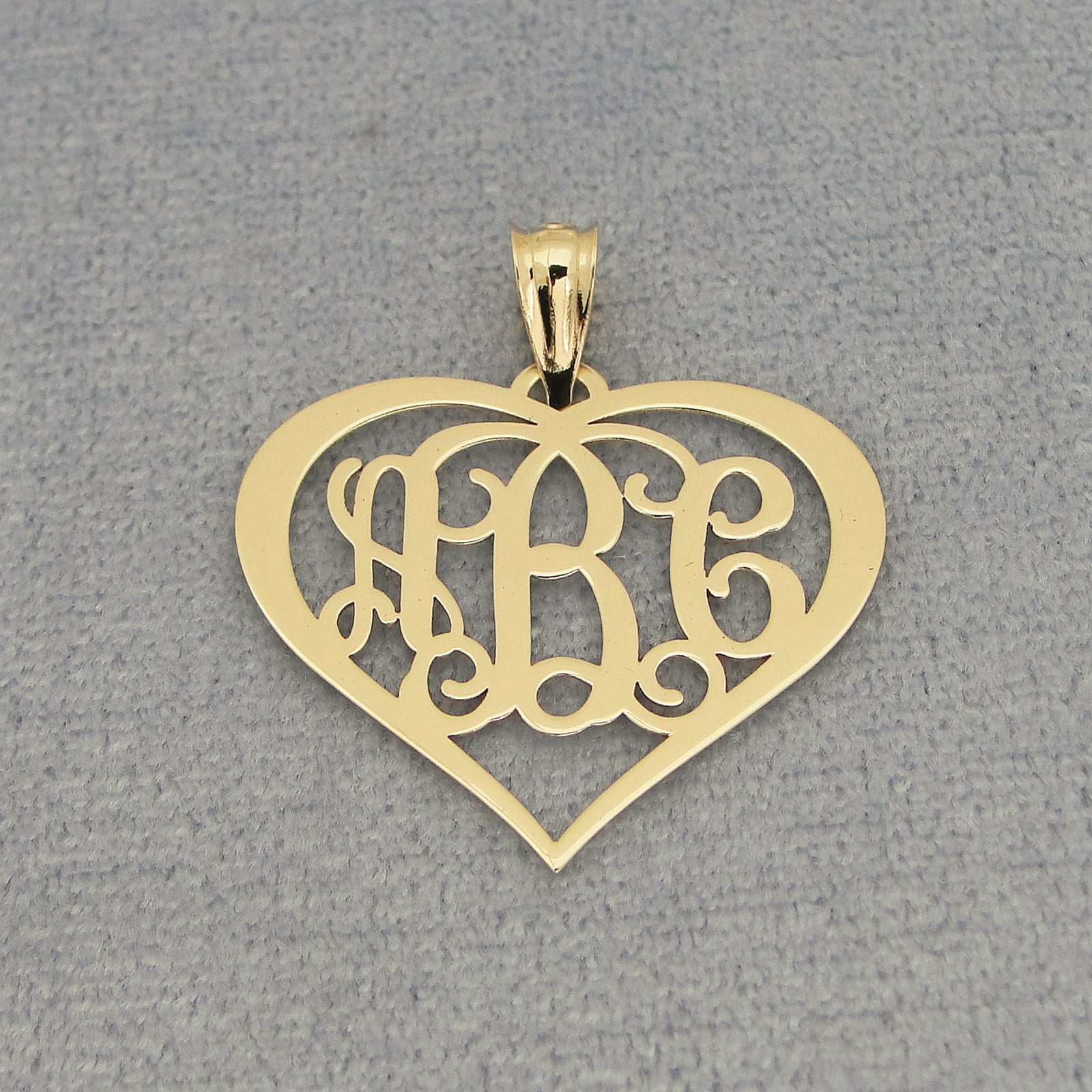 Close-up of custom laser-engraved three-initial solid gold heart monogram pendant
