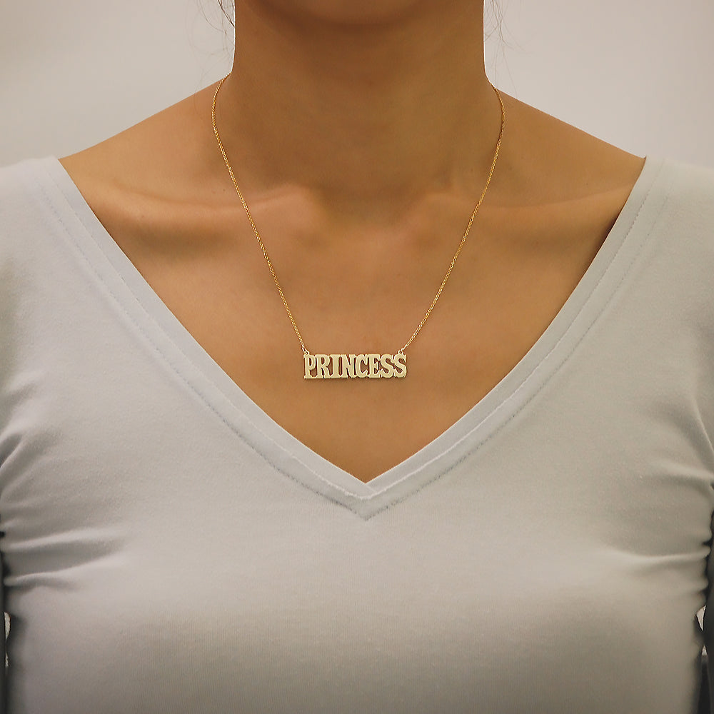 Woman wearing a handcrafted solid gold block letter name necklace with a modern custom pendant.