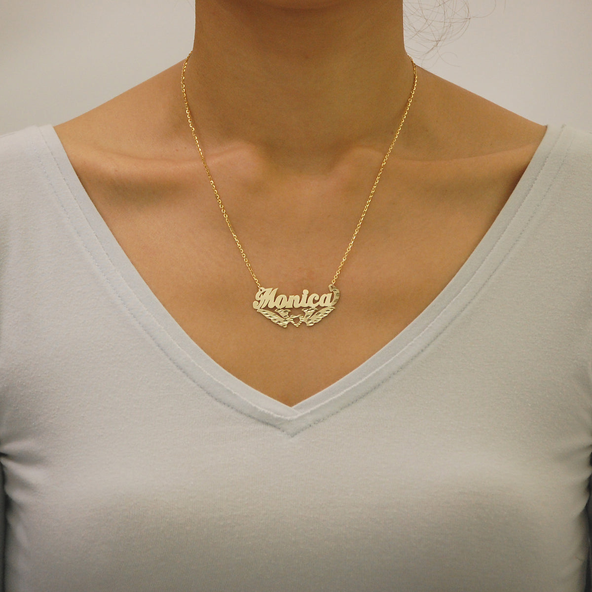 Woman wearing a personalized solid gold diamond-cut nameplate necklace handcrafted in Los Angeles.