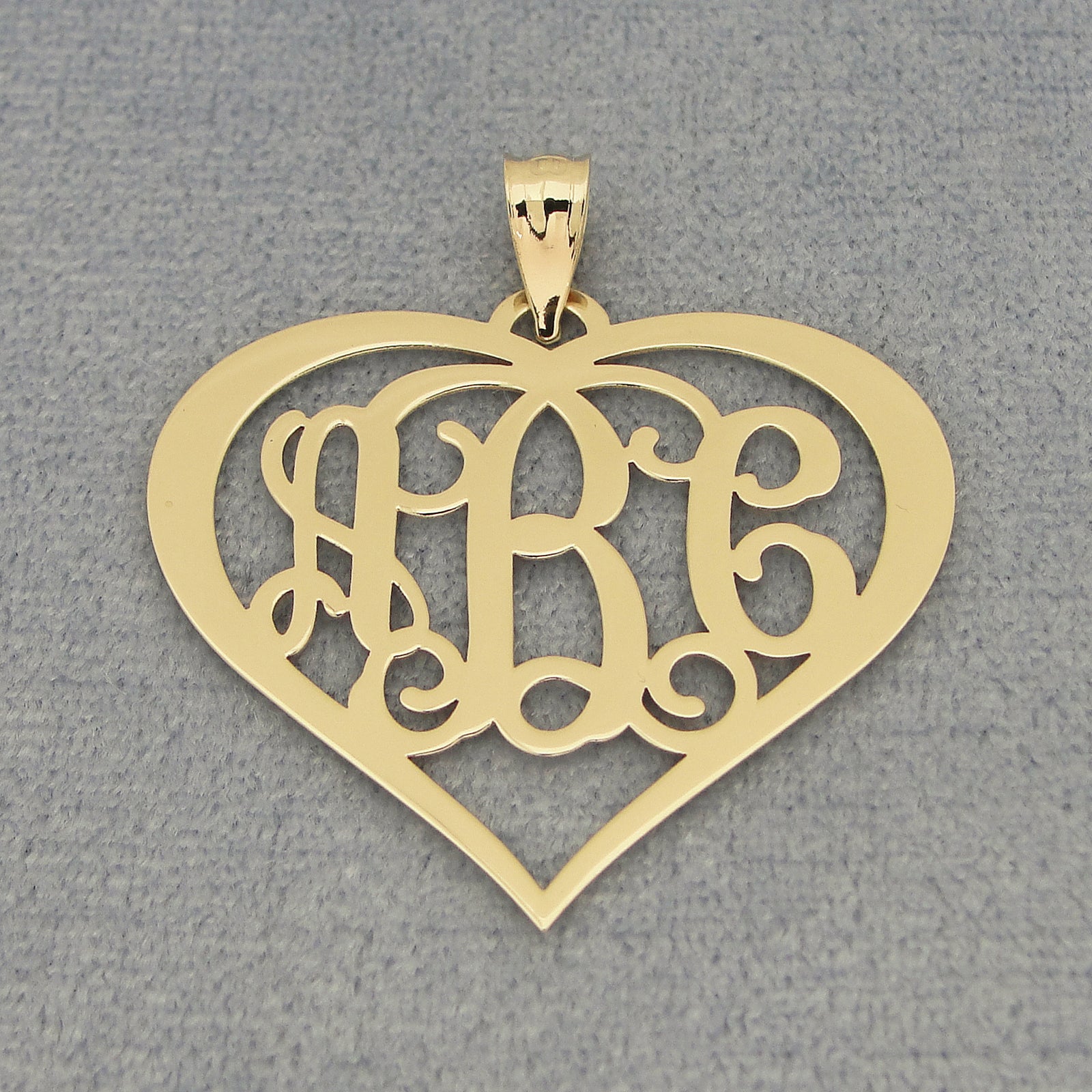 Close-up of a custom yellow gold 3-initial heart monogram pendant