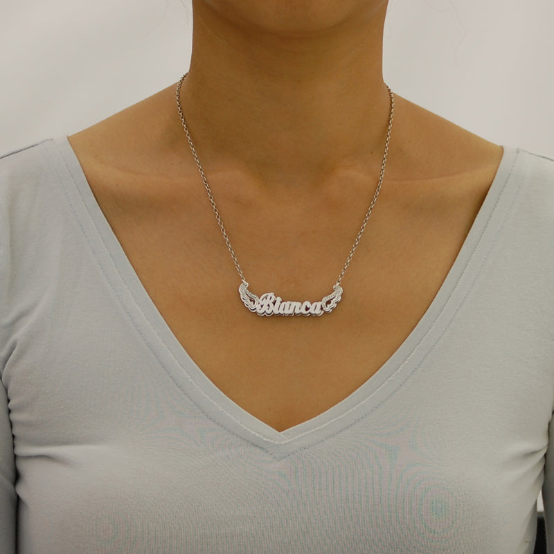 A model wearing a personalized sterling silver double-plate angel wings nameplate necklace on a delicate silver chain.