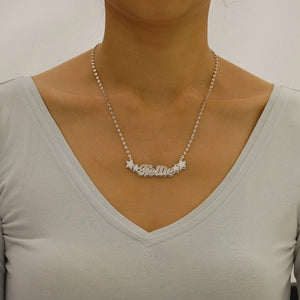 Model wearing a personalized sterling silver 3D "Kellie" nameplate necklace with star charms on an 18-inch rolo chain.