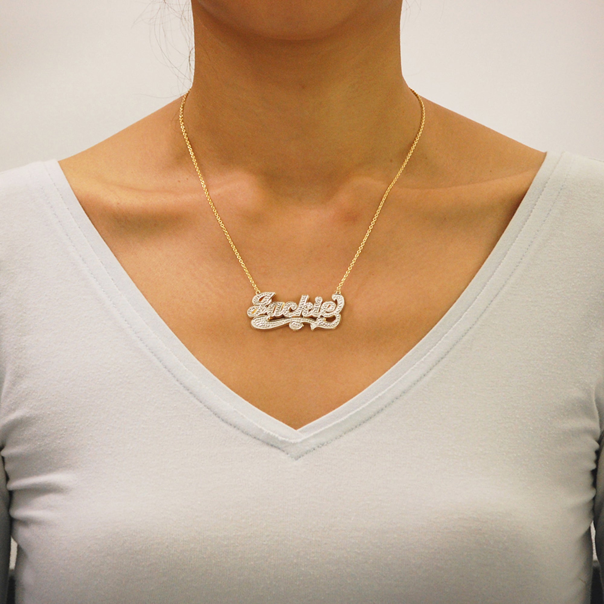 Custom solid gold iced out 3D double plate nameplate necklace worn on a gold chain.