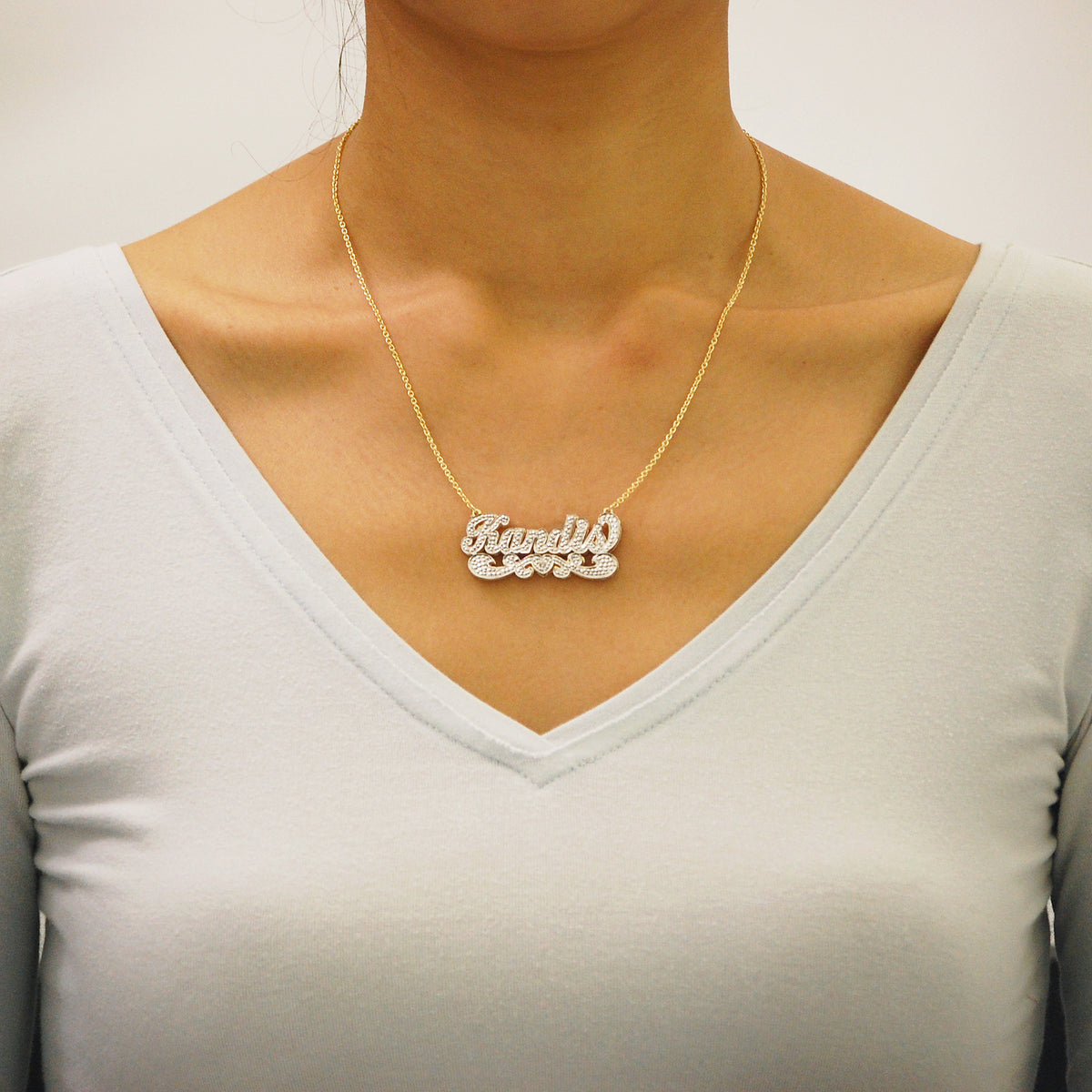 Woman wearing a custom solid gold 3D double plate diamond name pendant.