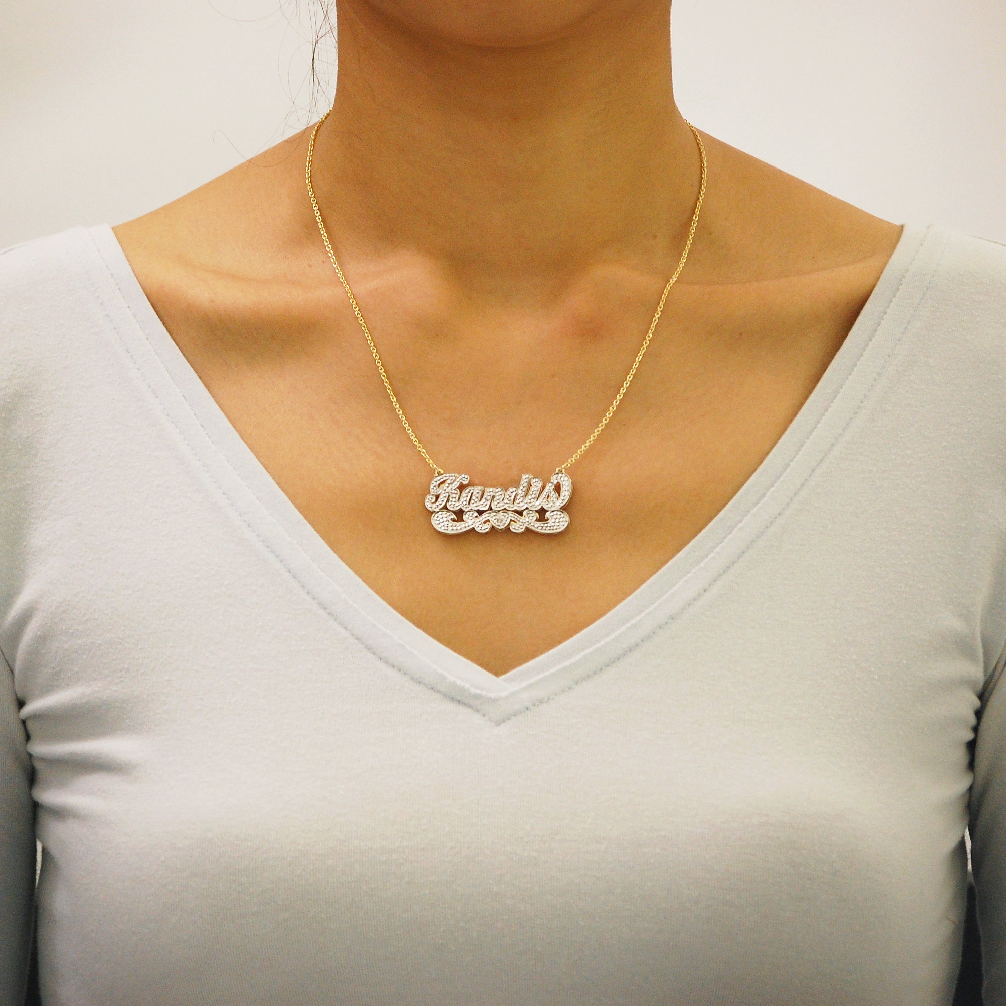 Woman wearing a custom solid gold 3D double plate diamond name pendant.
