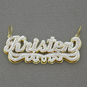 Close-up of hand-carved rhodium diamond accent details on 14k gold custom name pendant.