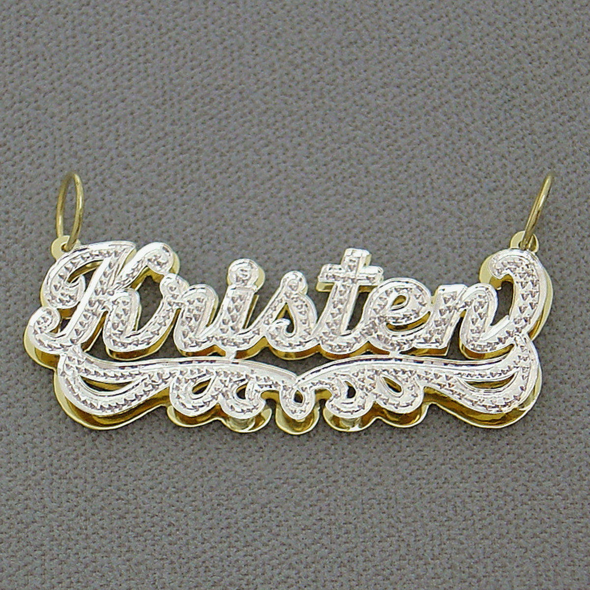 Close-up of hand-carved rhodium diamond accent details on 14k gold custom name pendant.