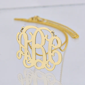 Close-up of a personalized solid gold 3-initial monogram necklace with a gold chain.