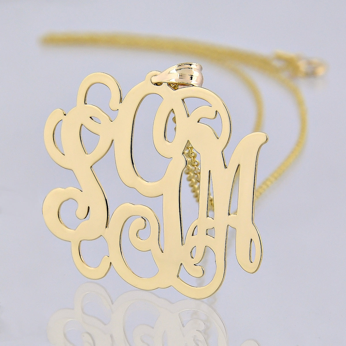 1.25-inch custom solid gold monogram pendant without a chain on a clean background.
