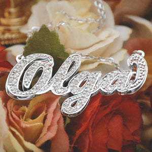 Close-up view of a custom 10K or 14K gold diamond name pendant spelling Olga with 3D double plate craftsmanship and hand-set diamonds.