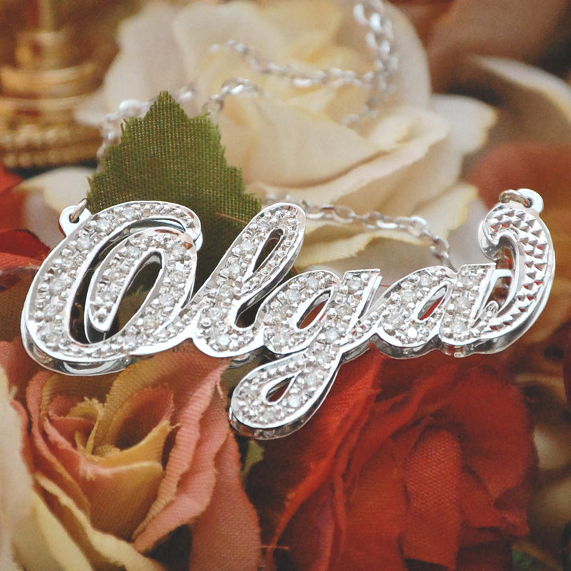 Close-up view of a custom 10K or 14K gold diamond name pendant spelling Olga with 3D double plate craftsmanship and hand-set diamonds.