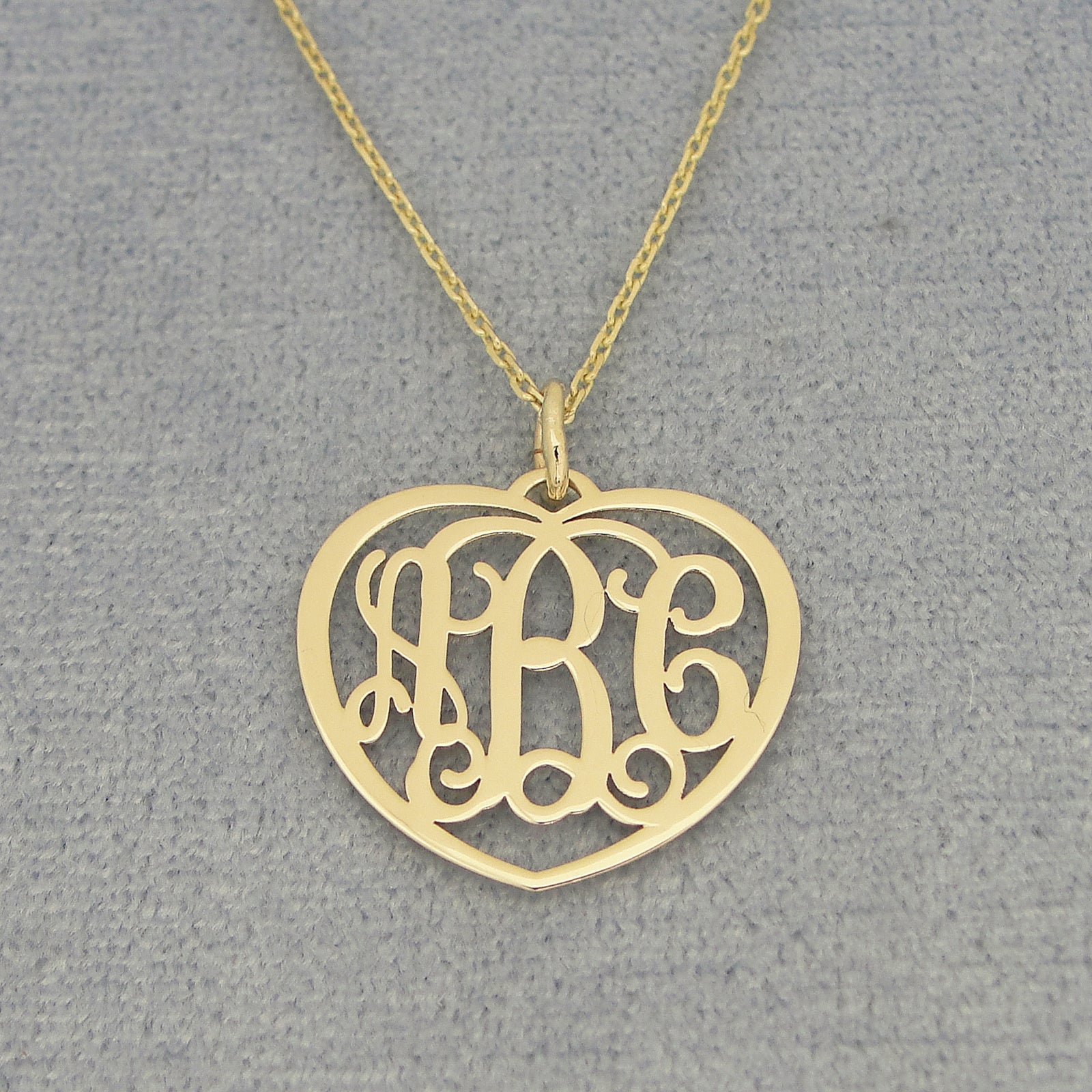 Small 10k or 14k solid gold heart monogram pendant with three custom initials on a gold chain.