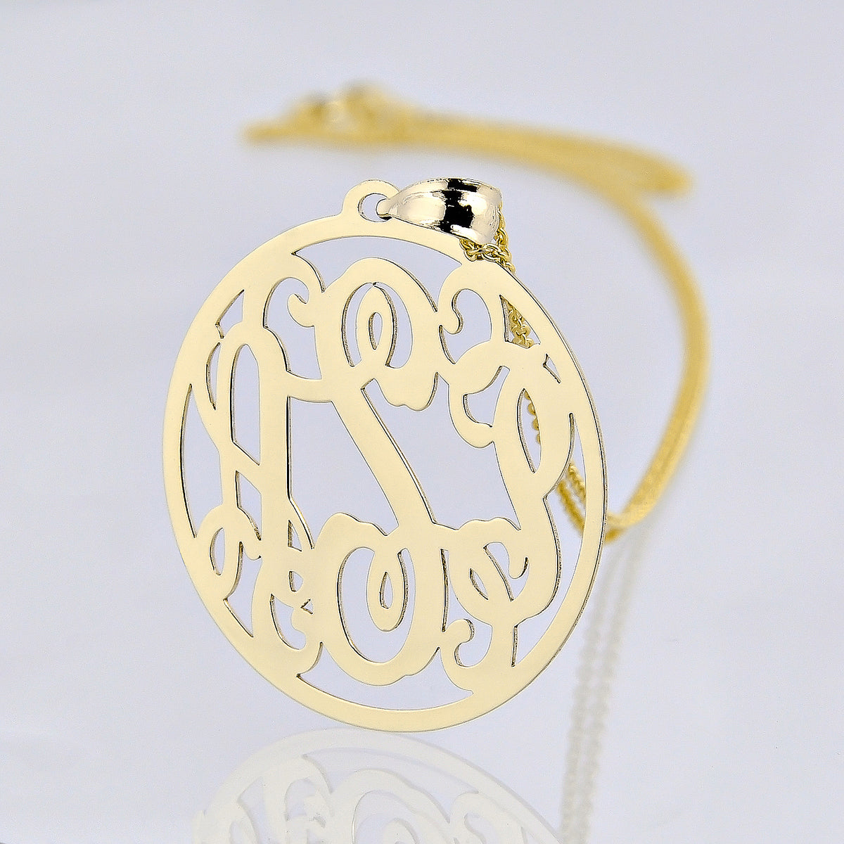 Close-up of a 10k or 14k solid gold three-initial circle monogram pendant with a gold chain