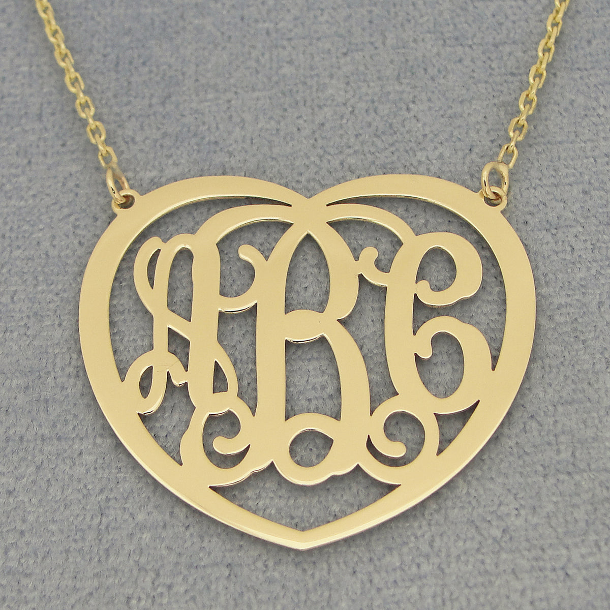 Close-up of a laser-cut 10k or 14k solid gold heart monogram pendant with three personalized initials.