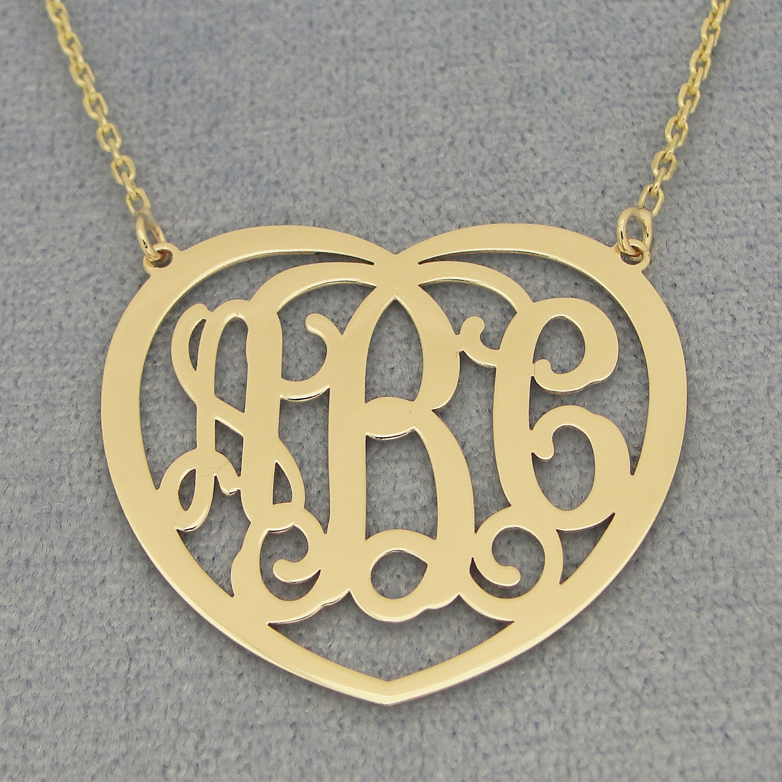 Close-up of a laser-cut 10k or 14k solid gold heart monogram pendant with three personalized initials.