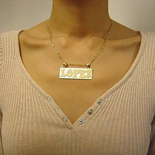 Model wearing a personalized solid gold rectangular name pendant on a yellow gold chain.