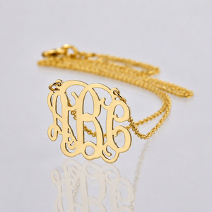 Angled detail view of personalized mini 3-initial monogram necklace showing 14k yellow gold thickness and polish