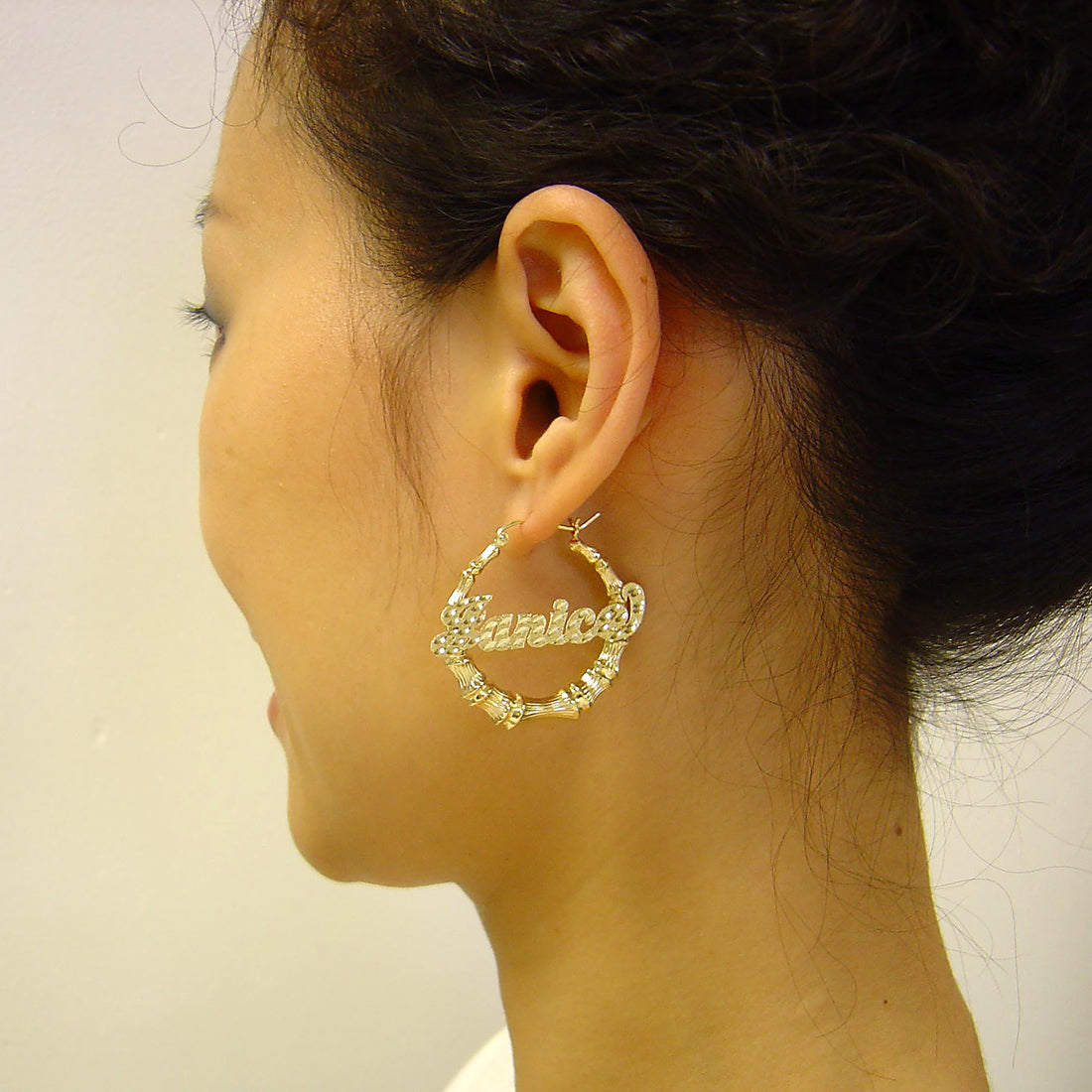 1 3/8 inches gold bamboo hoop earrings with personalized diamond cut script name 'Janice' on the model