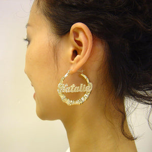 Woman wearing 1.7 inch custom diamond cut nameplate bamboo hoop earring in solid gold