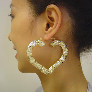 Model wearing 3 inch 10K gold puffy heart door knocker hoop earrings