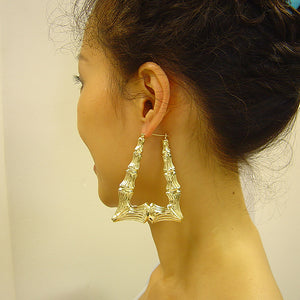 Woman wearing extra large 2.3 inch 10K yellow gold rectangular bamboo door knocker hoop earrings