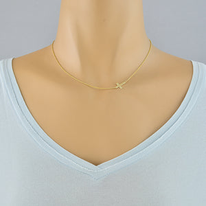A delicate gold chain necklace with a small cross pendant