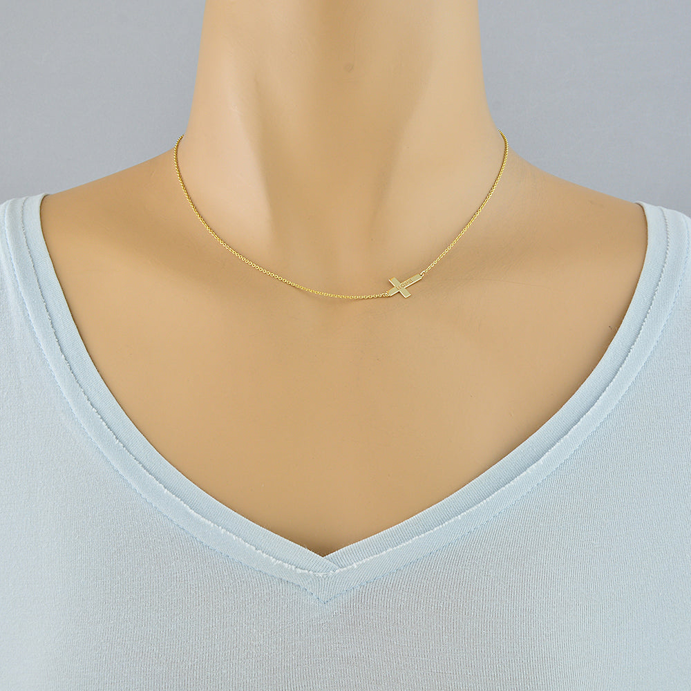 A delicate gold chain necklace with a small cross pendant