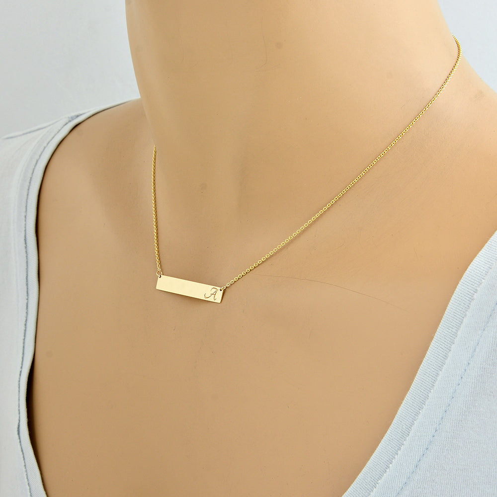 wearing 1.25 inch solid gold horizontal name bar necklace on 15 inch chain