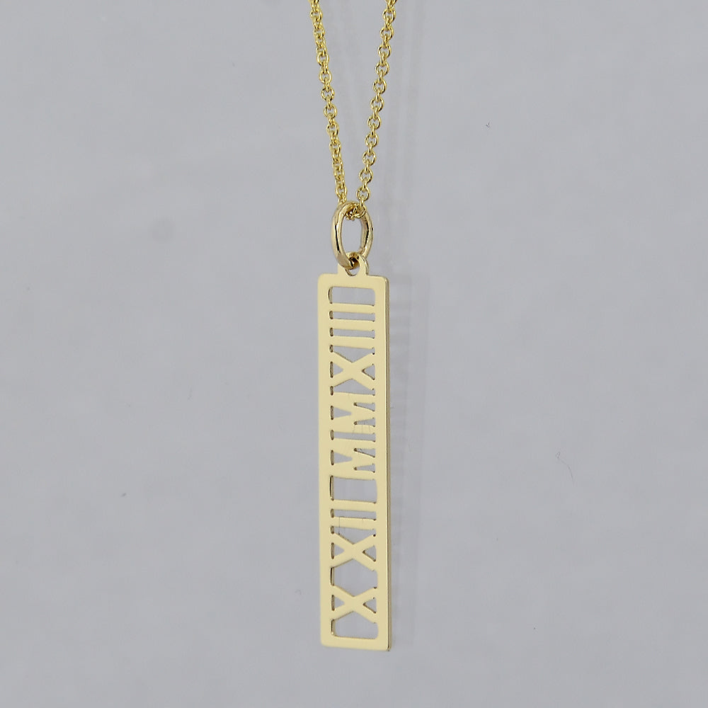 A gold necklace featuring a vertical rectangular pendant with Roman numerals cut out