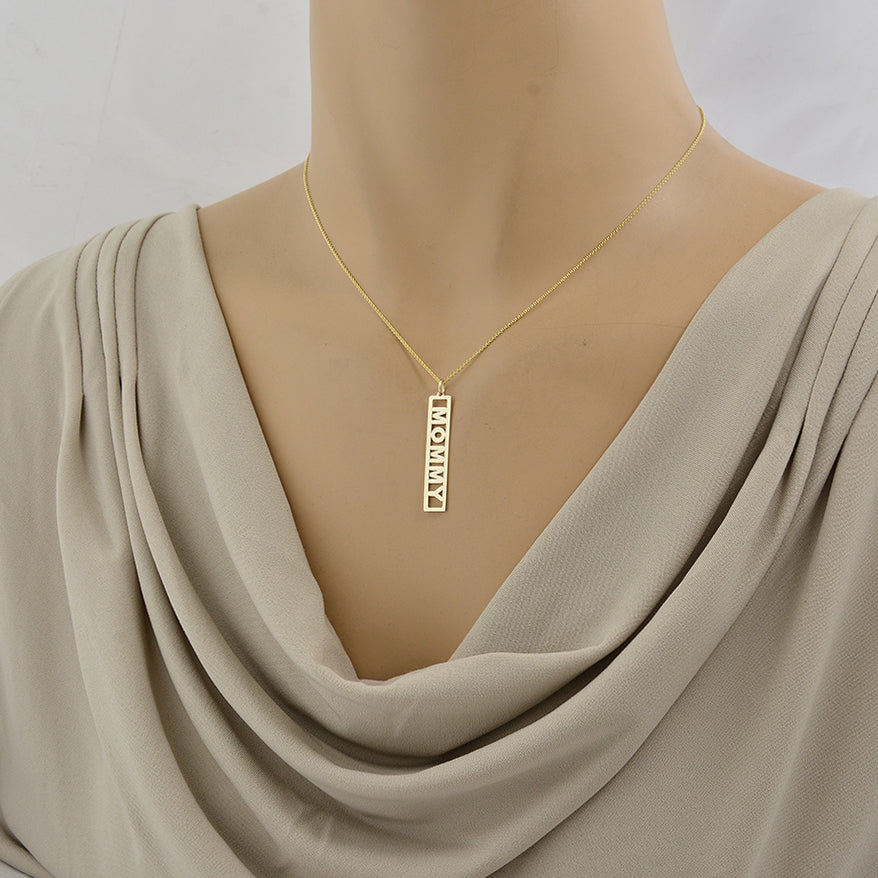 A gold chain necklace with a vertical rectangular pendant engraved