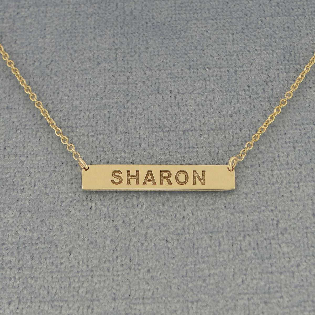 Close-up of 7/8 inch extra small white gold horizontal nameplate bar necklace with high-contrast laser engraving