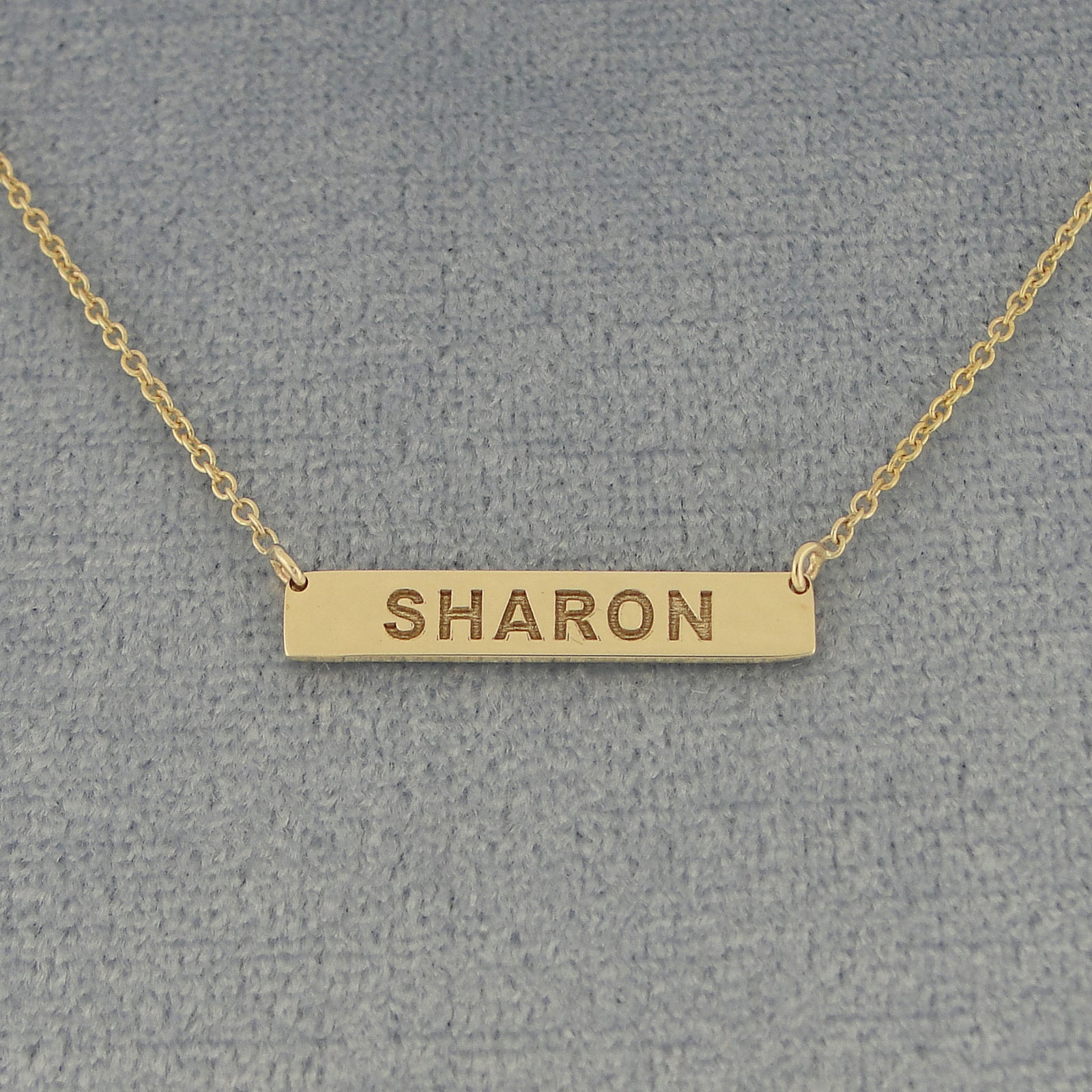 Close-up of 7/8 inch extra small white gold horizontal nameplate bar necklace with high-contrast laser engraving