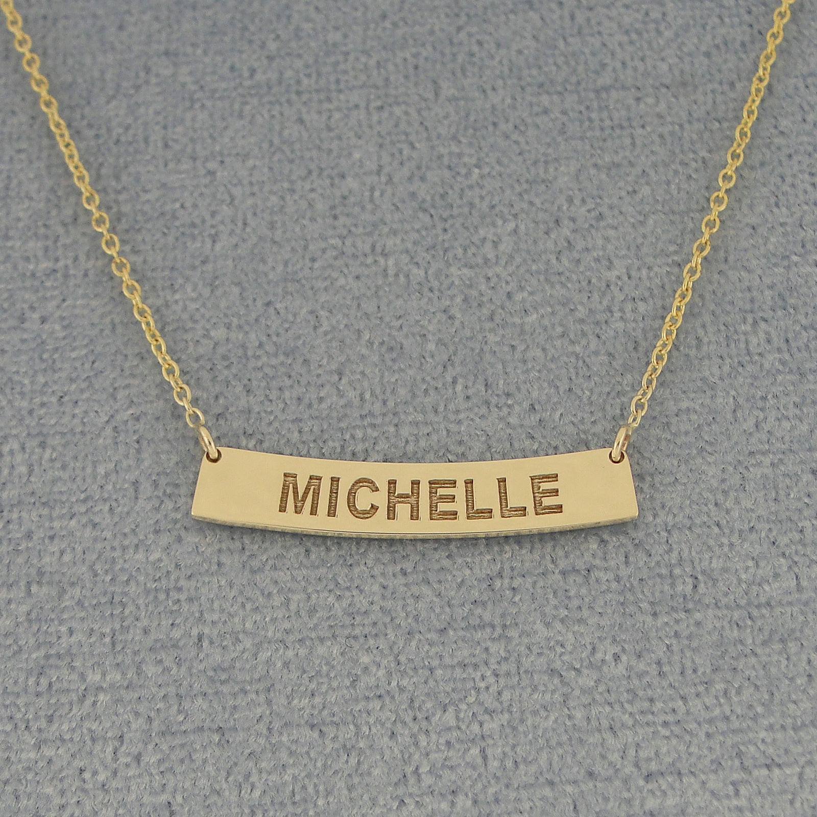 Close up of custom laser engraved solid gold horizontal curve bar pendant