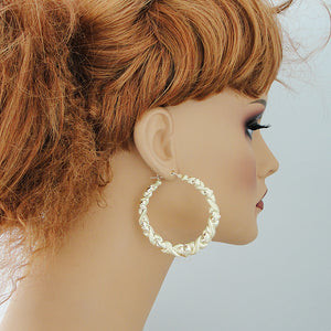 10K yellow gold puffed XO heart doorknocker hoop earrings with diamond-cut pattern on mannequin.