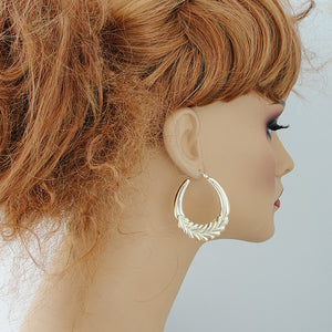 wearing 1.5-inch large 10k yellow gold wheat door knocker hoop earrings