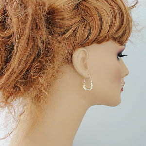 Baby wearing 10k yellow gold puffy doorknocker drop earrings showing size and fit