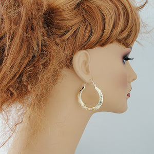 Pair of 10K yellow gold puffy hollow doorknocker drop earrings 1.5 inch on mannequin.