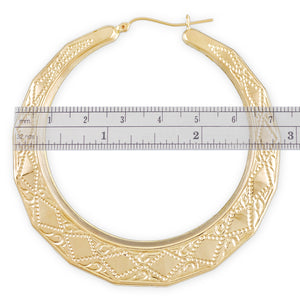 10K yellow gold patterned doorknocker hoop earrings shown next to a ruler measuring 2.9 inches in diameter