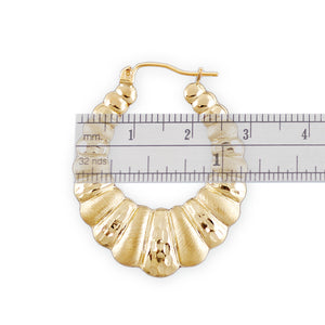 Close-up of diamond-cut texture on 10K gold hollow puffy doorknocker hoop earrings
