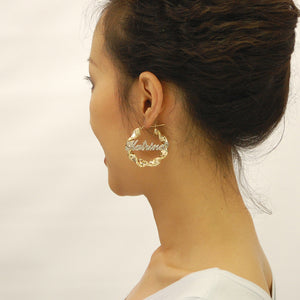 Woman wearing 1.6 inch 10K gold personalized iced out name twisted hoop earrings