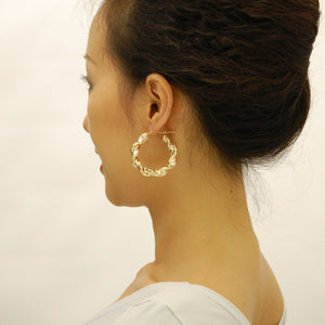 Side view of 1.6 inch 10K yellow gold 8mm thick twisted hoop earrings on model